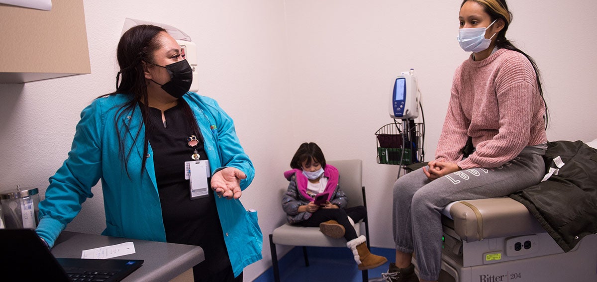 Doctor talks to patiend while entering visit infomation into medical record.